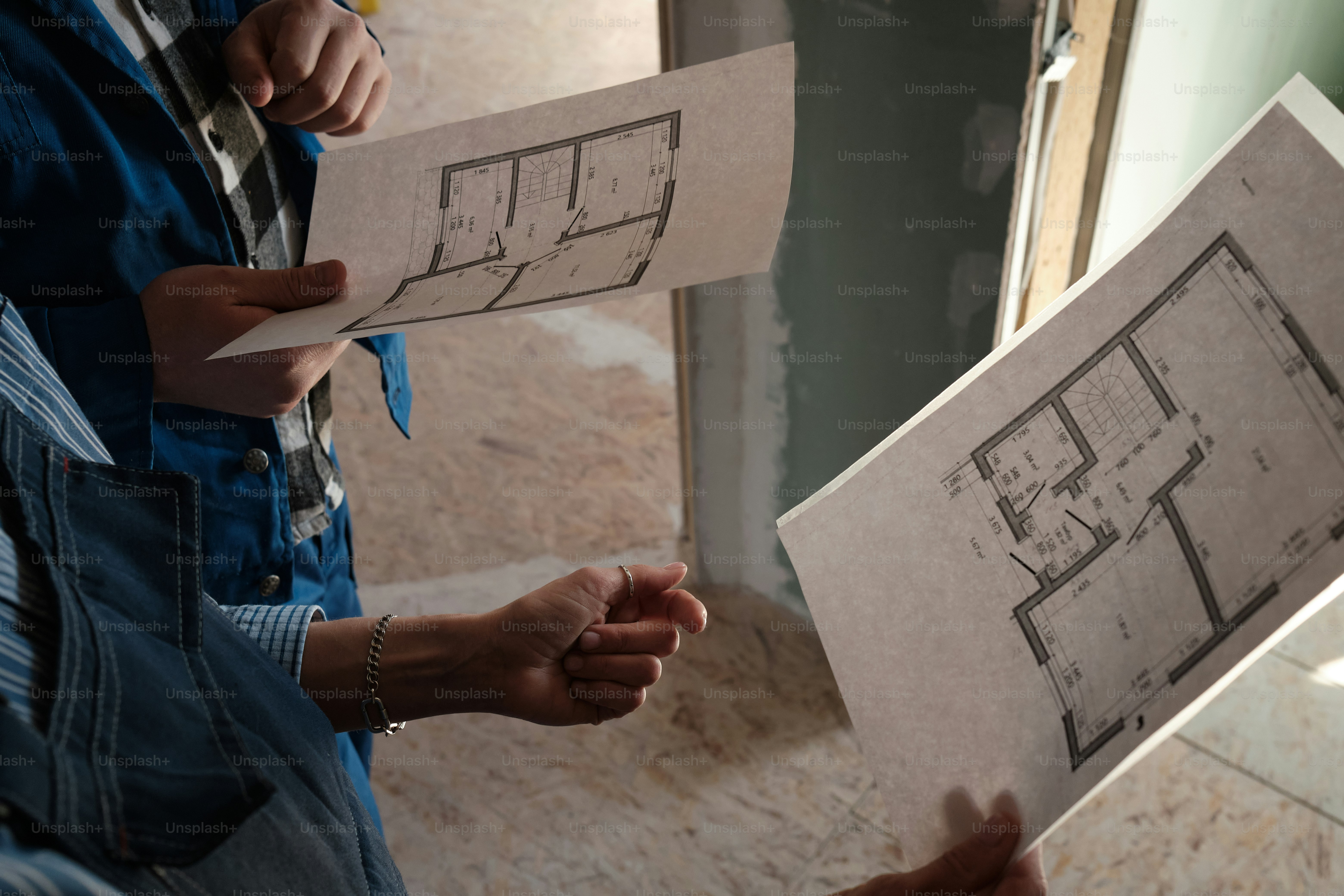 hands of construction workers with a plan of a house under construction