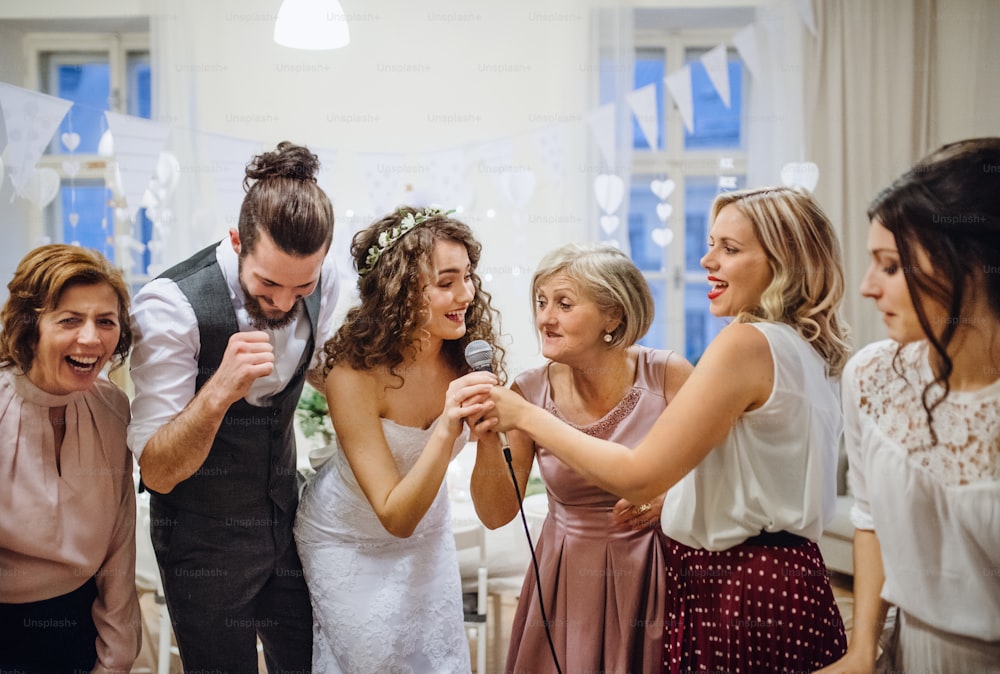 A young cheerful bride with other guests dancing and singing on a wedding reception.