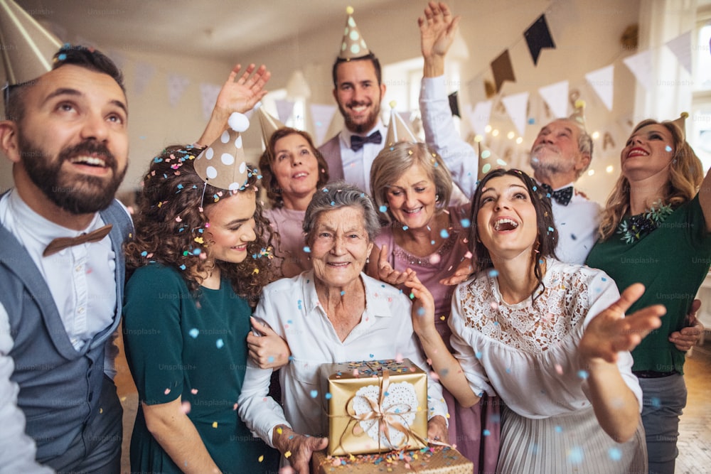 A portrait of multigeneration family with presents standing indoor on a birthday party.