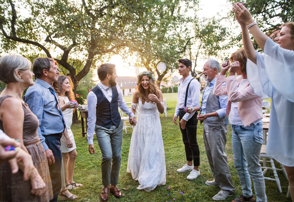 Braut, Bräutigam und ihre Gäste bei der Hochzeitsfeier draußen im Hinterhof. Familienfeier.