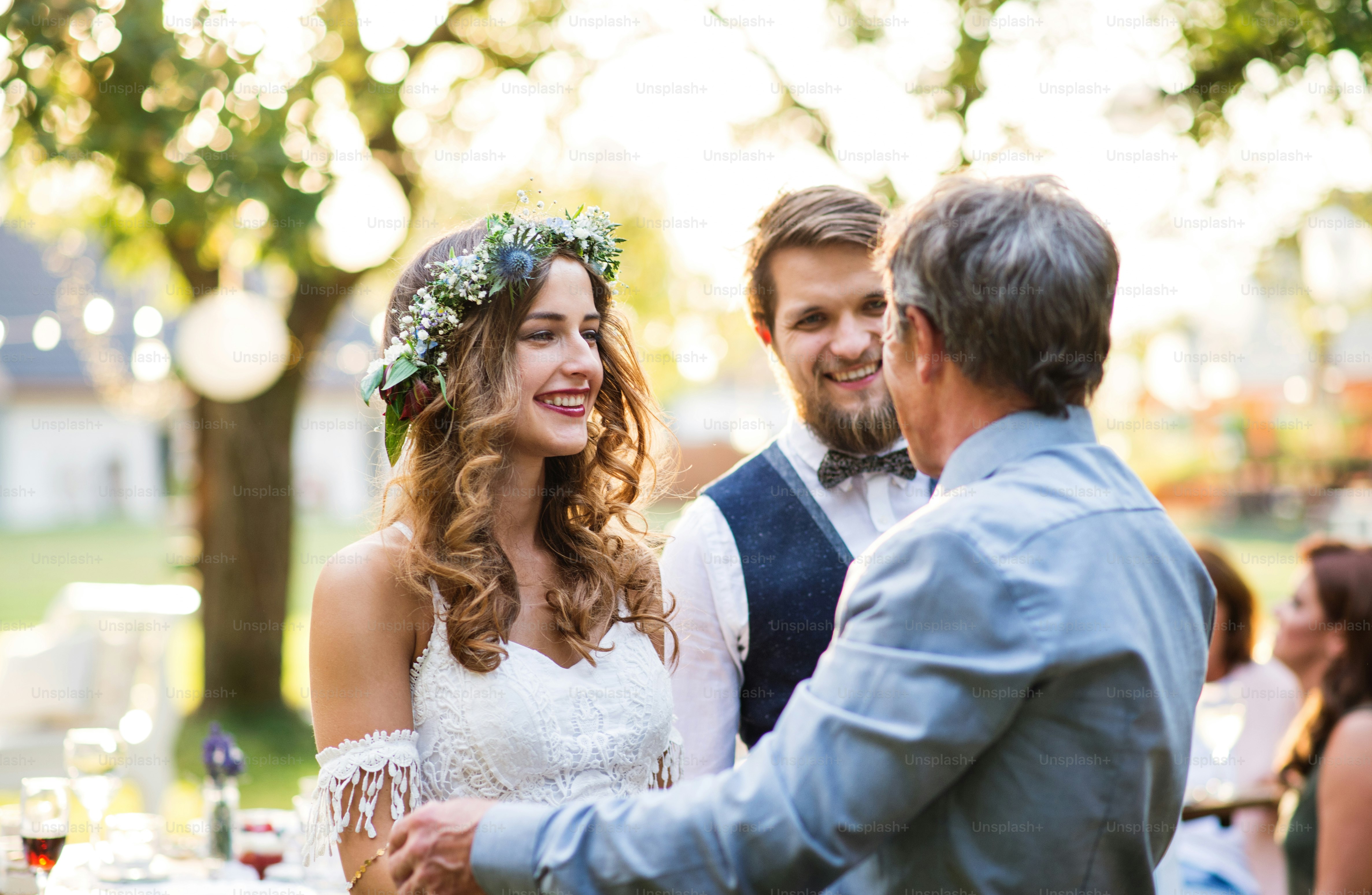 Un père âgé félicitant les mariés lors de la réception de mariage à l’extérieur dans la cour.