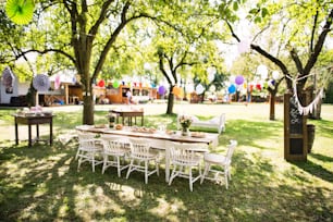 Table dressée pour une fête de jardin ou une célébration à l’extérieur. Fleurs et collations sur la table décorée dans le jardin.