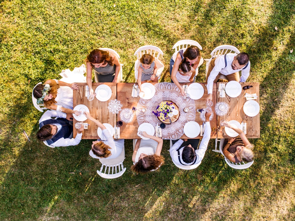 Ricevimento di nozze all'aperto nel cortile sul retro. Sposa e sposo con una famiglia intorno al tavolo. Veduta aerea.