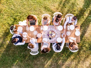 Réception de mariage à l’extérieur dans la cour. Mariée et marié avec une famille autour de la table. Vue aérienne.