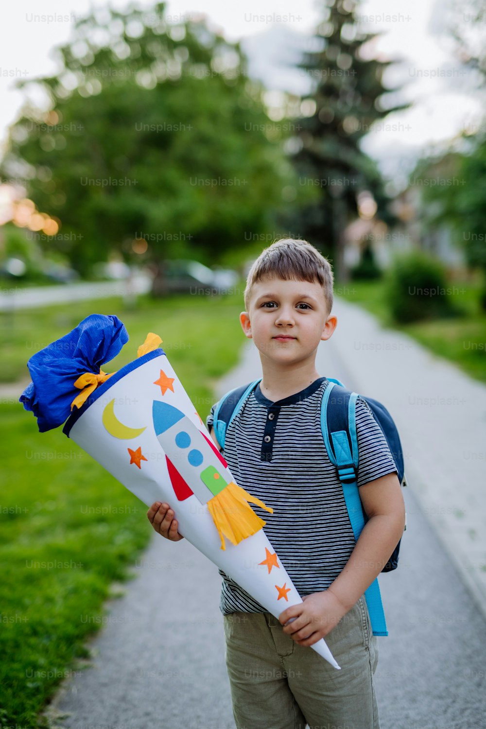Un petit garçon avec une sacoche d’école le premier jour d’école, tenant un cône d’école avec des cadeaux