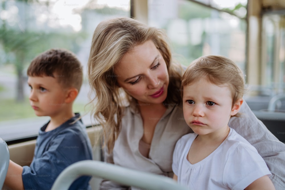 Una madre joven con niños pequeños que viajan en tranvía en verano, los desplazamientos y el concepto de estilo de vida sostenible.