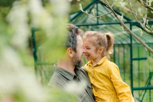 Ein Vater mit seiner kleinen Tochter, die sich vor einem Öko-Gewächshaus und einem nachhaltigen Lebensstil verbindet.