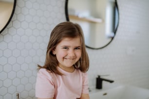 Un retrato de una niña feliz en el baño, mirando a la cámara.