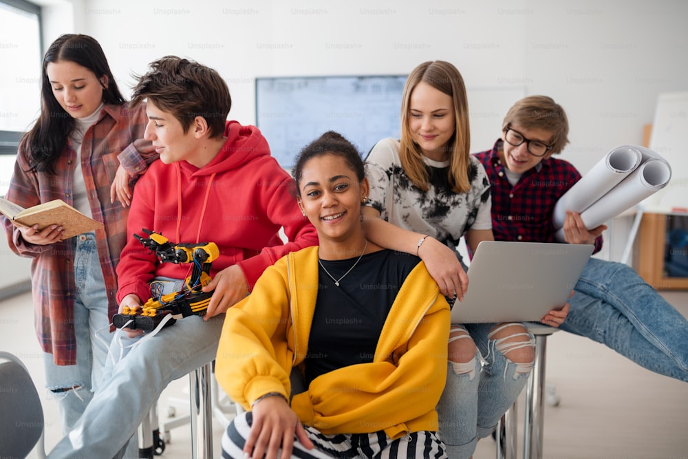 Group of students sitting and posing together in a robotics classroom