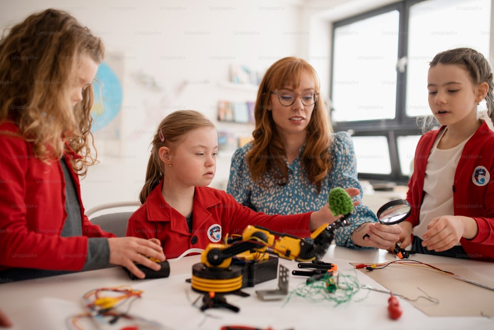 Un grupo de niños con un joven profesor de ciencias que programa juguetes eléctricos y robots en el aula de robótica