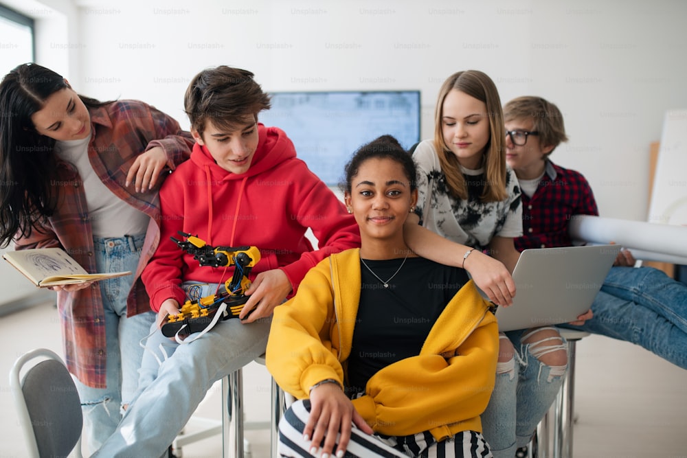 Grupo de alunos sentados e posando juntos em uma sala de aula de robótica