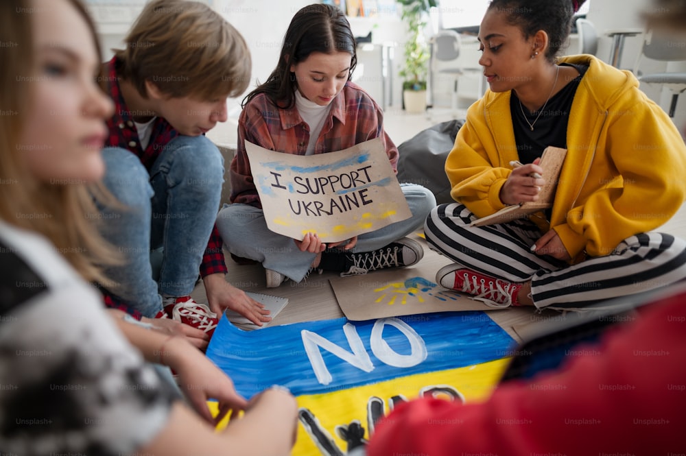 Studenti adolescenti seduti in cerchio in un'aula con manifesti per sostenere l'Ucraina, nessun concetto di guerra.
