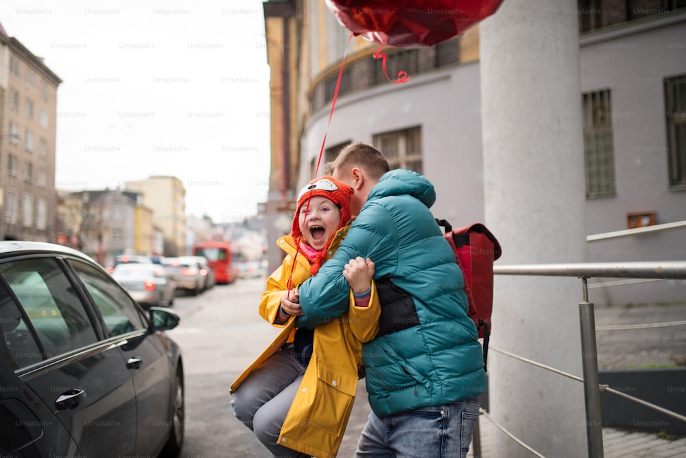 Un padre che porta la sua piccola figlia con la sindrome di Down a scuola, all'aperto in strada.