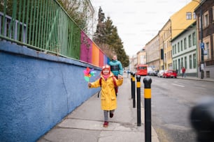 Un père emmène sa petite fille atteinte du syndrome de Down à l’école, à l’extérieur dans la rue.