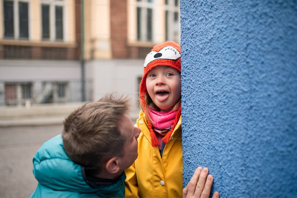 A father with his little daughter with Down syndrome outdoors in street in winter