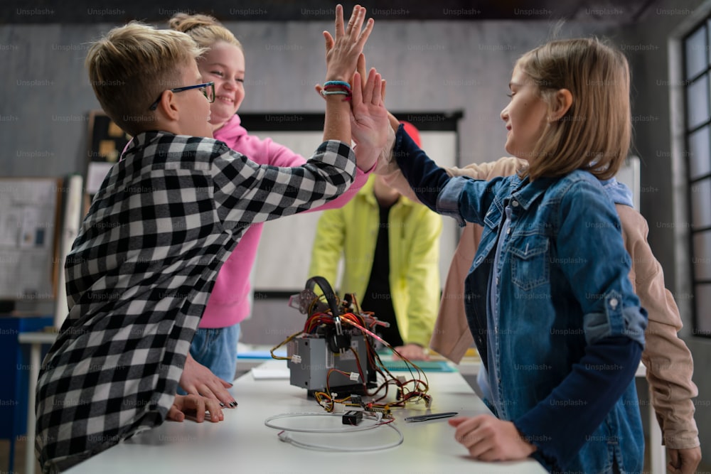 Un grupo de niños felices con su profesor de ciencias con juguetes eléctricos y robots en el aula de robótica
