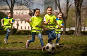 都市公園で屋外でサッカーをする幸せな小さな子供たち、グループ教育のコンセプトを学ぶ。