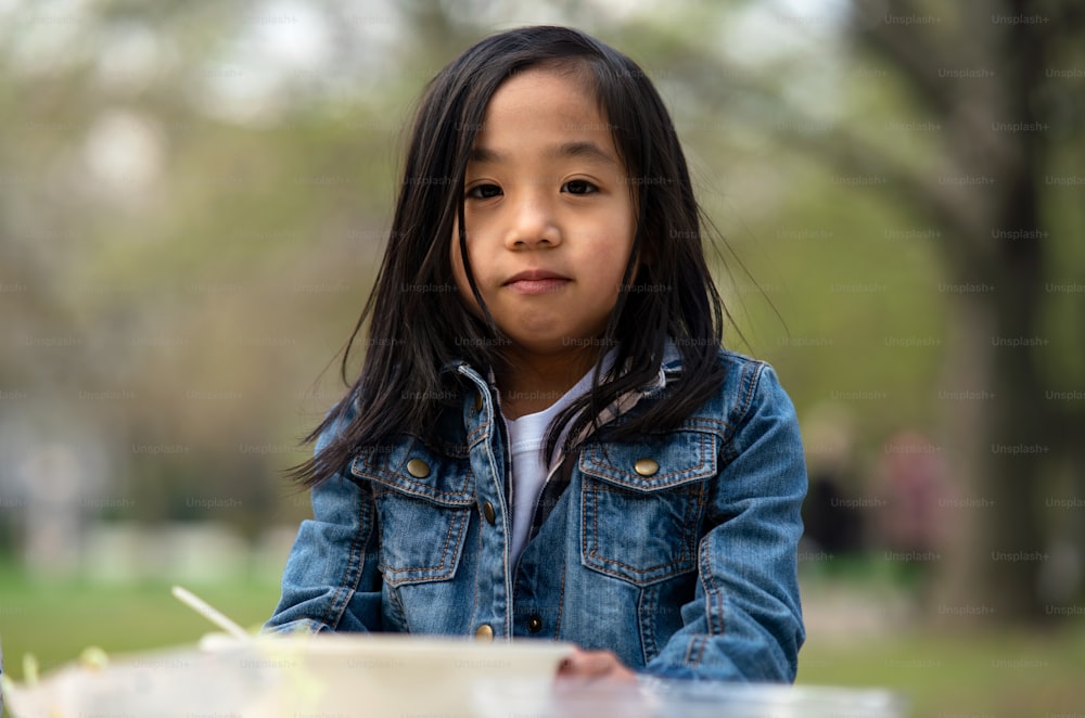 Porträt eines kleinen Kindes, das im Freien im Stadtpark in die Kamera schaut, Lerngruppen-Bildungskonzept.