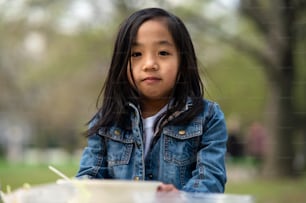 Portrait of small child looking at camera outdoors in city park, learning group education concept.