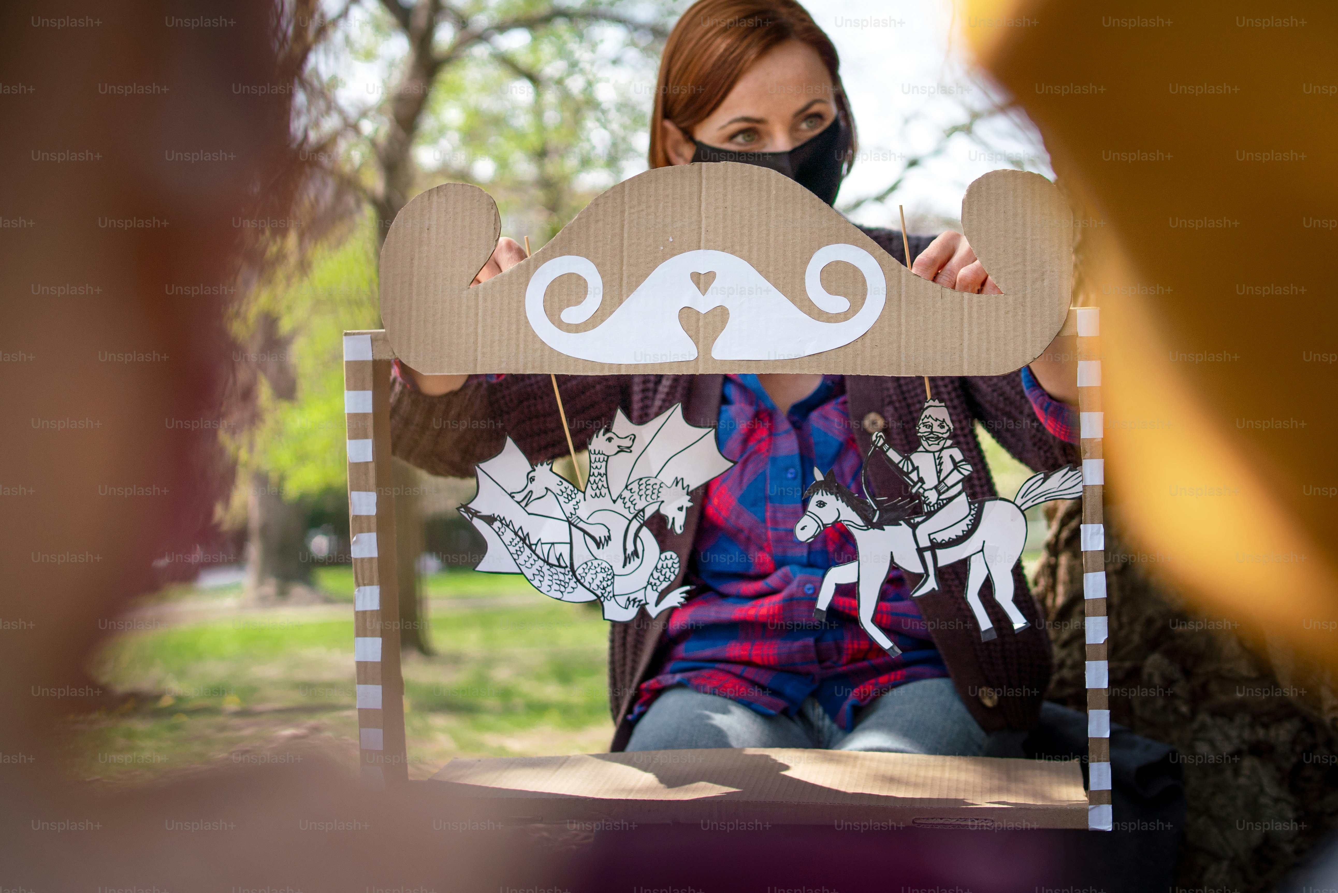 A teacher with small children sitting outdoors in city park, learning group education and coronavirus concept.