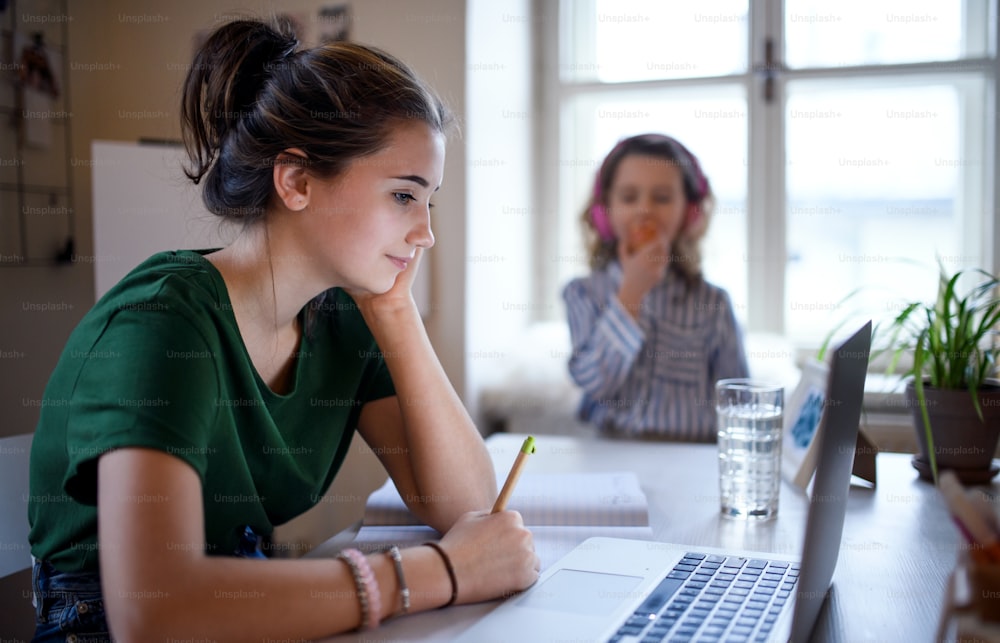 Teenager schoolgirl with face mask learning online indoors at home, coronavirus concept.