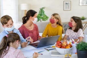 Group of homeschooling children with parent teacher studying indoors, coronavirus concept.