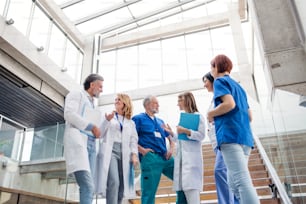 Group of cheerful doctors standing on staircase medical conference, talking.