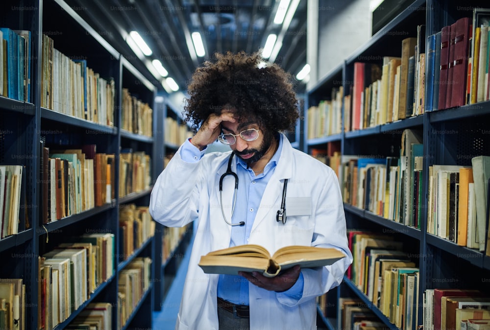 Portrait of male doctor standing in library, studying information about corona virus.