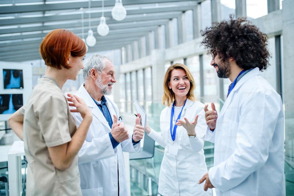 회의에 서 있는 의사들, 문제를 논의할 때 웃고 있는 의료진.