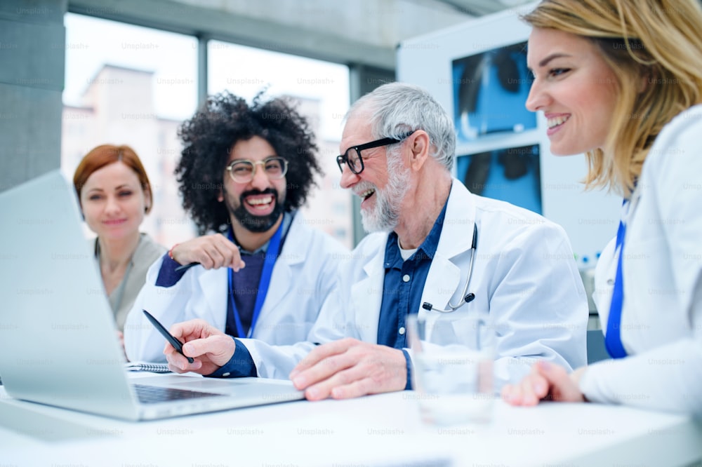 A group of doctors with laptop on conference, medical team discussing issues.