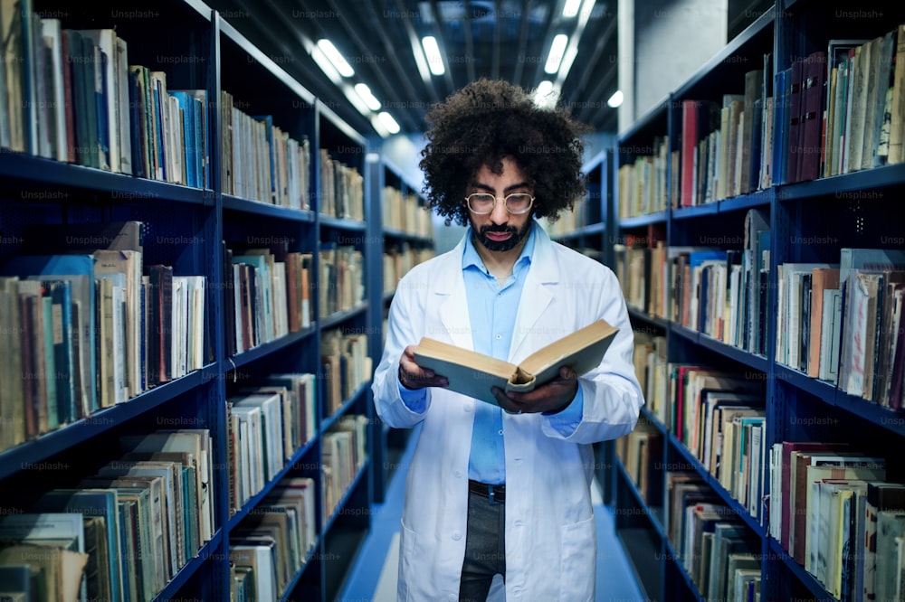 Retrato de un médico de pie en la biblioteca, estudiando información sobre el virus corona.