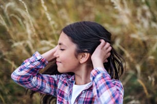 A side view of school child standing on field trip in nature, headshot. Copy space.