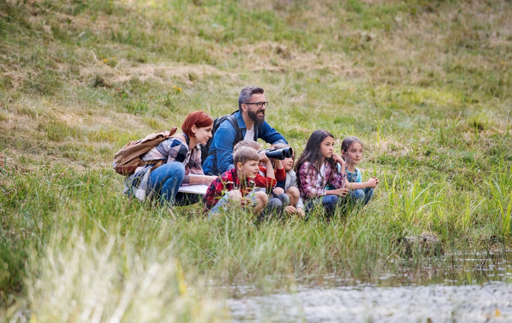 Um grupo de crianças pequenas em idade escolar com professor em viagem de campo na natureza.