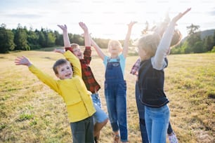 Portrait of group of school children standing on field trip in nature, playing.