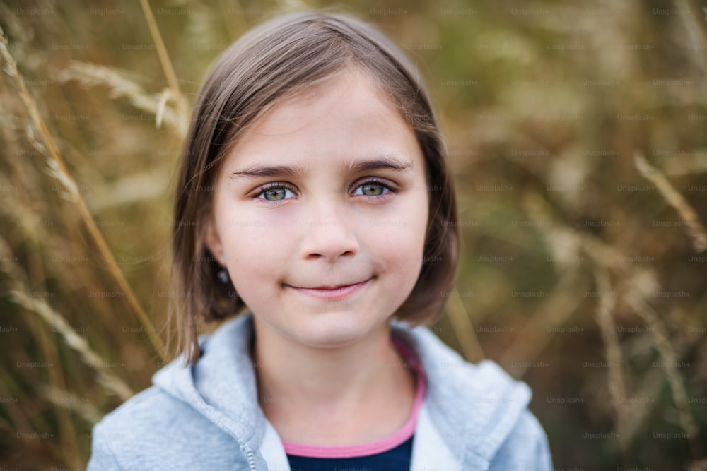 Portrait of school child standing on field trip in nature, looking at camera.