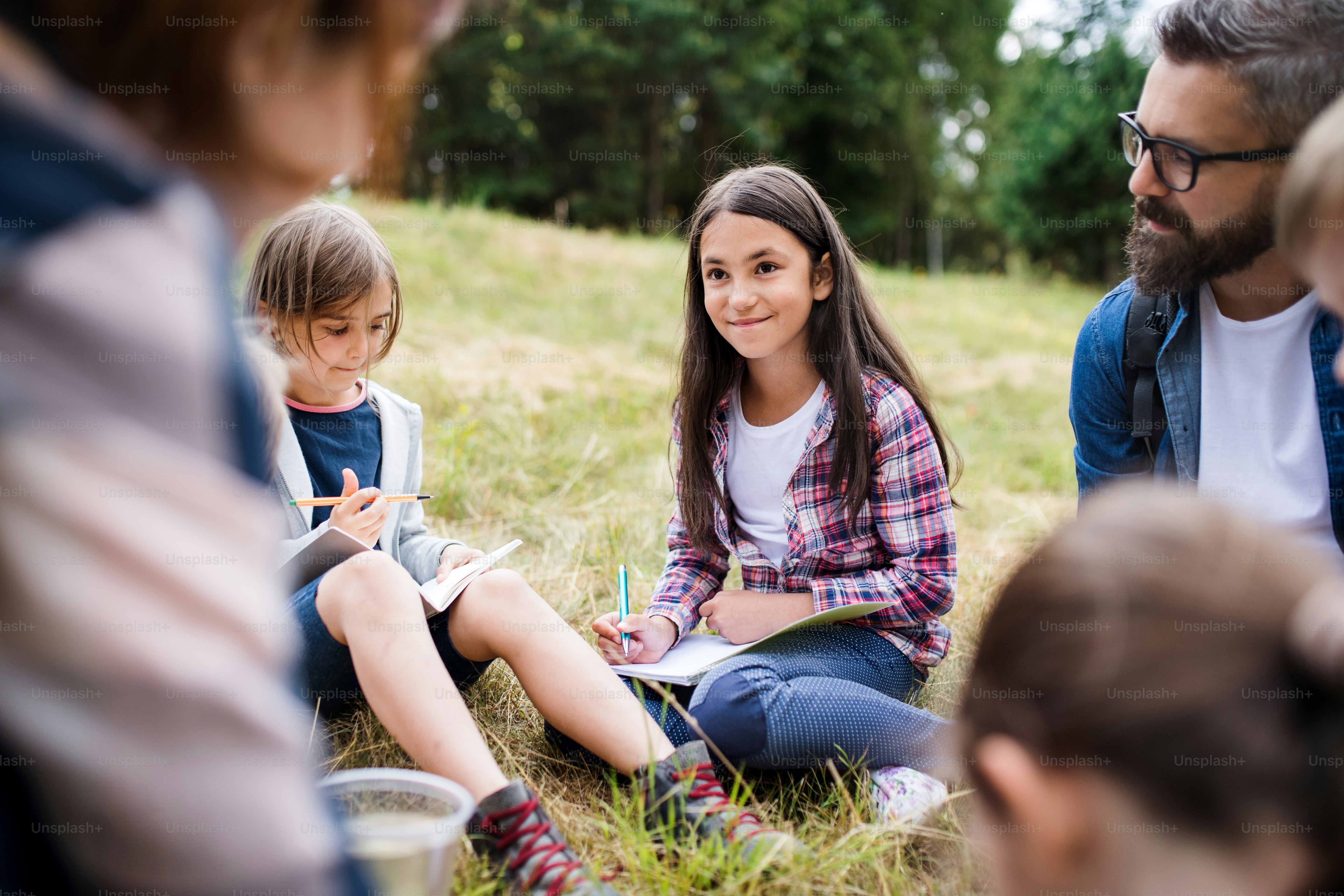 Um grupo de crianças pequenas em idade escolar com professor em viagem de campo na natureza, aprendendo ciências.