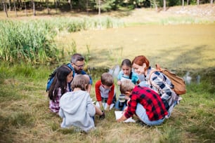 A group of small school children with teacher on field trip in nature.