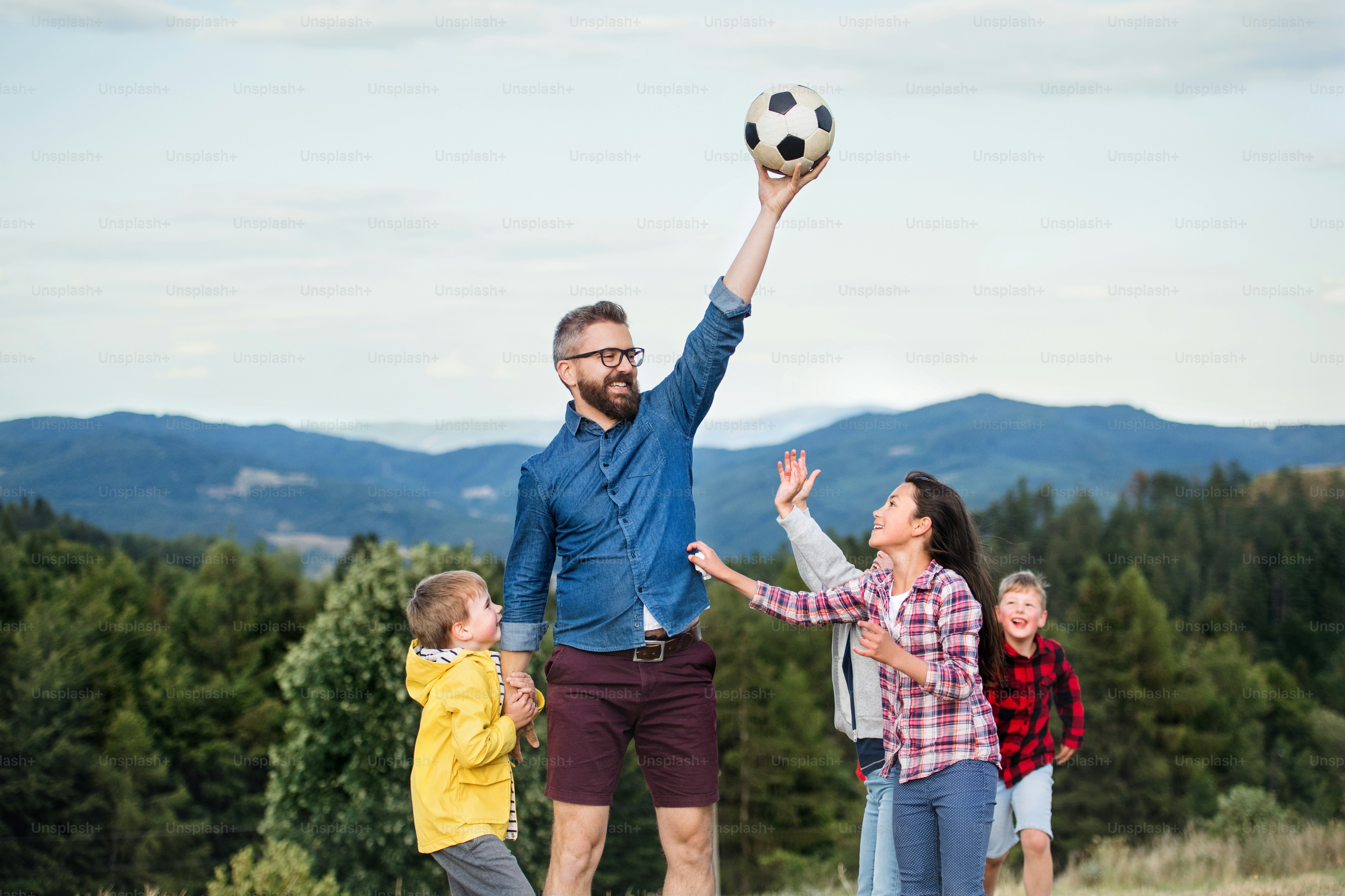 Un grupo de niños pequeños de la escuela con el maestro en la excursión en la naturaleza, jugando con una pelota.