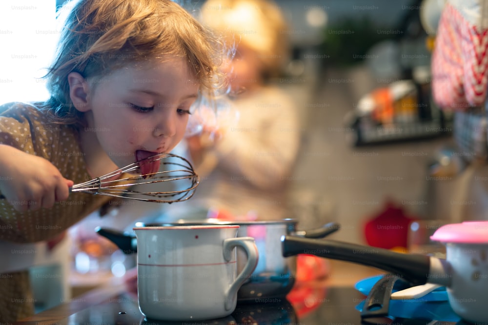 Bambino e ragazza felici in casa in cucina a casa, aiutando con la cucina.