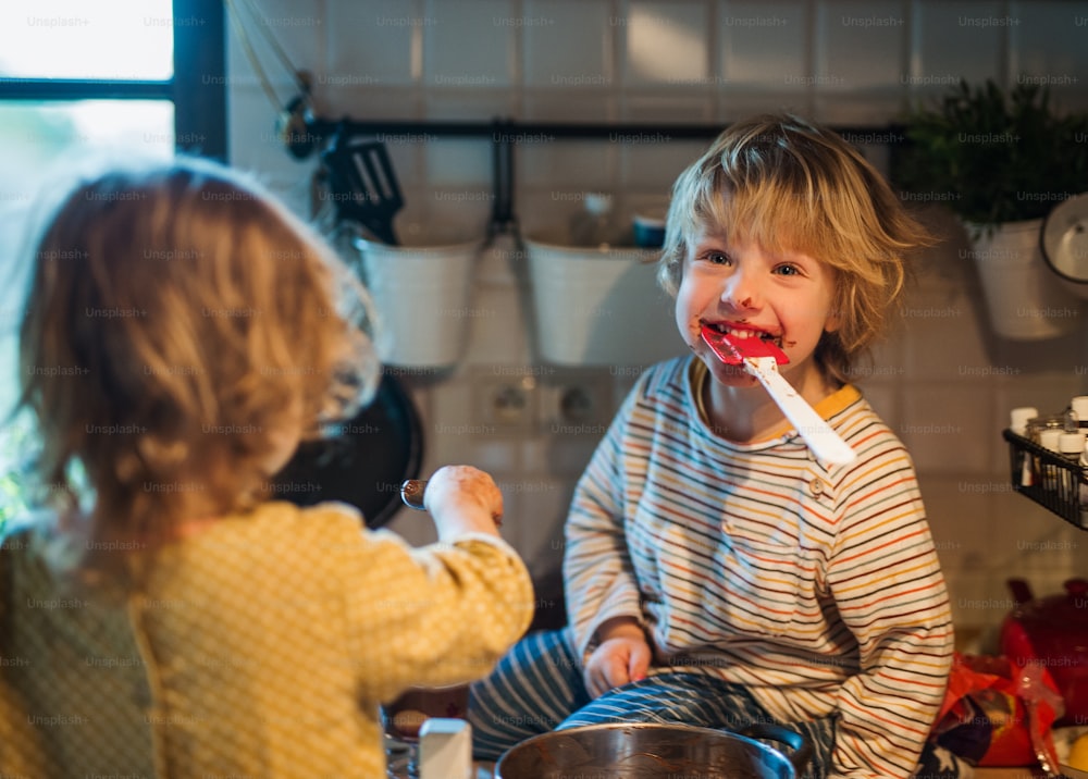 Niño y niña felices en el interior de la cocina en casa, ayudando con la cocina.