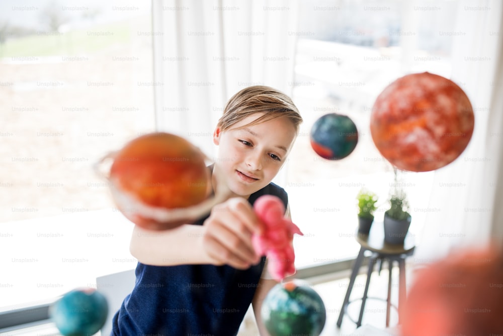 Ein kleiner Junge mit Modell des Sonnensystems drinnen, spielend.