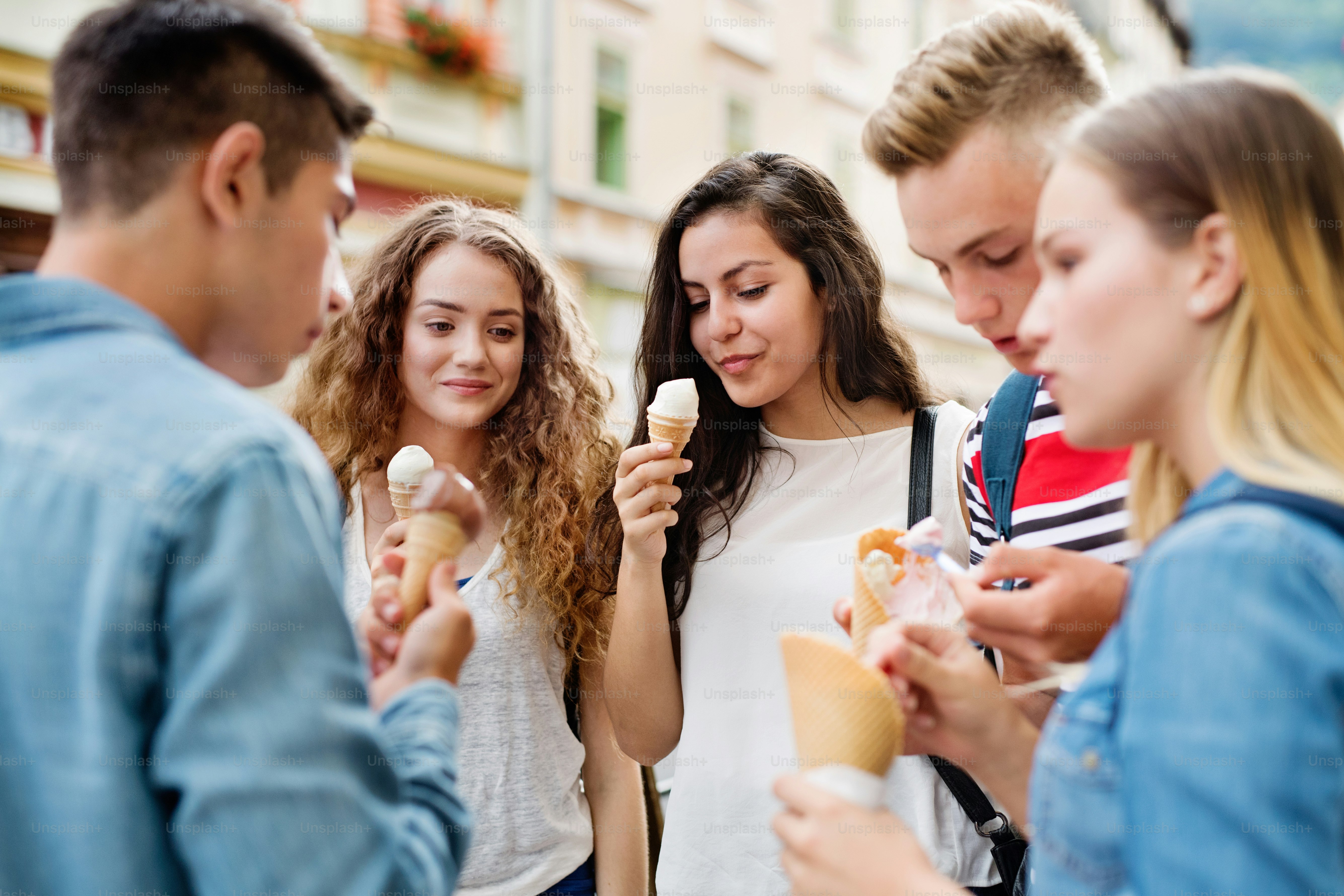 Grupo de estudiantes adolescentes atractivos en la ciudad comiendo helado.