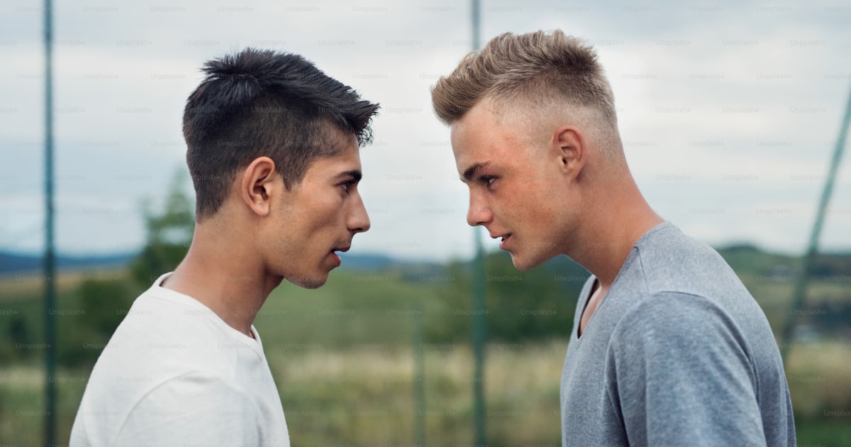 Two handsome teenage boys outdoors on playground looking at each other ...