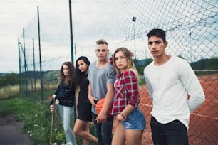 Group of attractive teenagers outdoors at the playground with basketball.