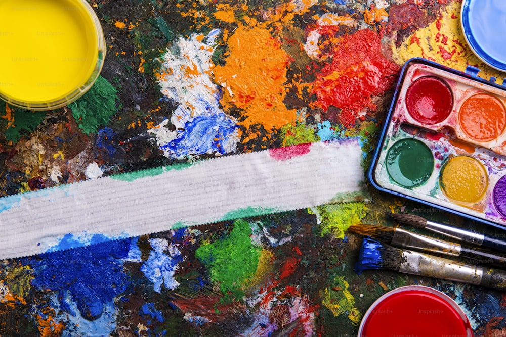 Desk of an artist with watercolor paints and paintbrushes.