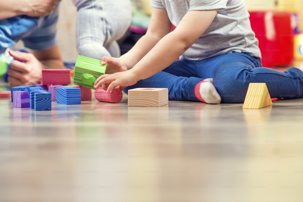 Young hipster playing with his daughters on a floor