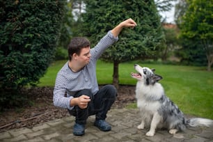 Portrait of cheerful down syndrome adult man training dog pet outdoors in backyard.