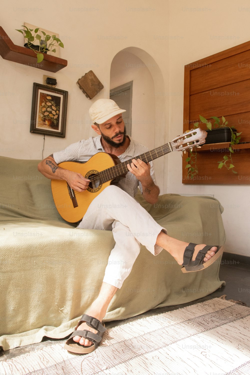 Un hombre sentado en una cama tocando una guitarra