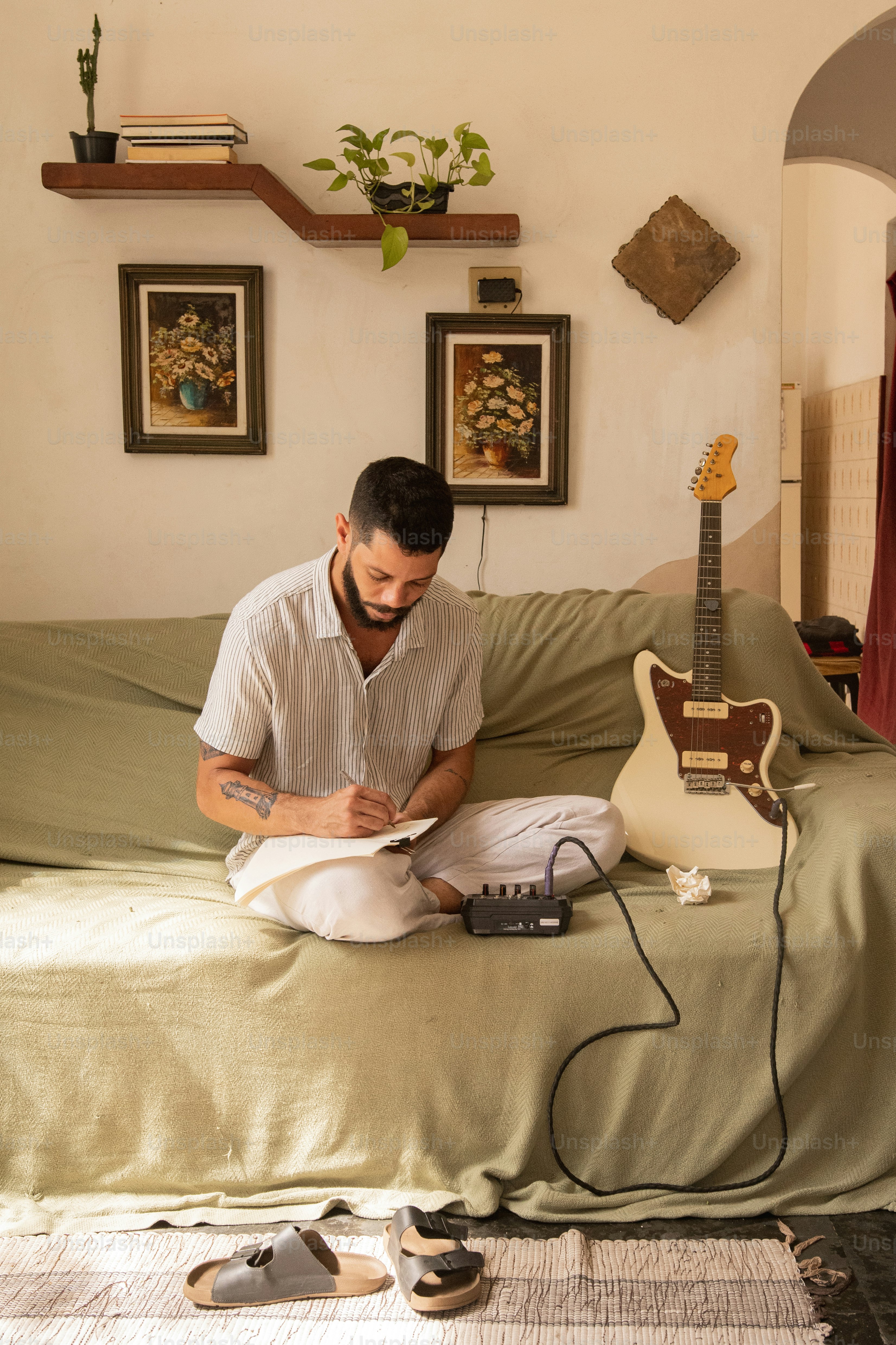 a man sitting on a couch next to a guitar