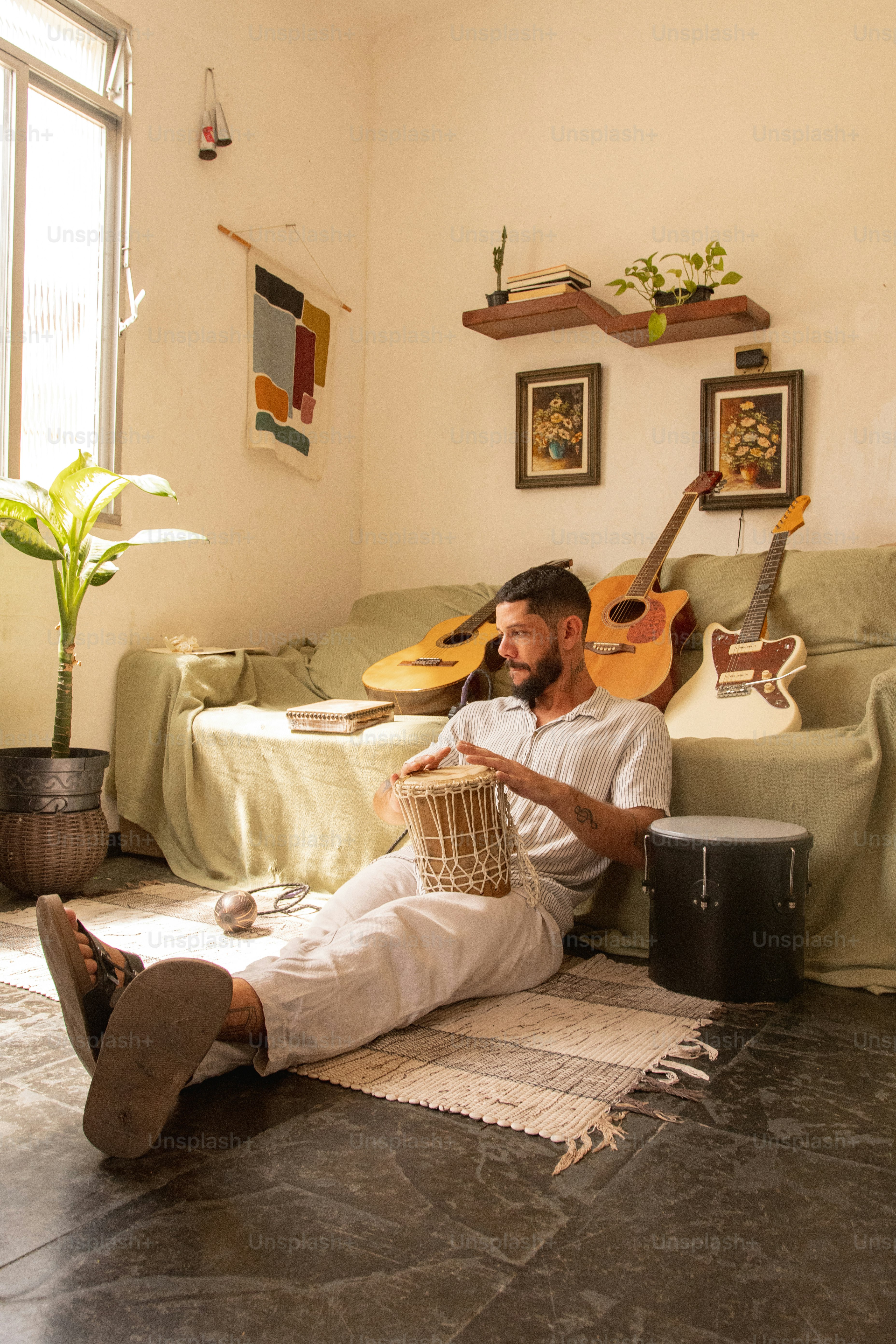a man sitting on the floor playing a musical instrument
